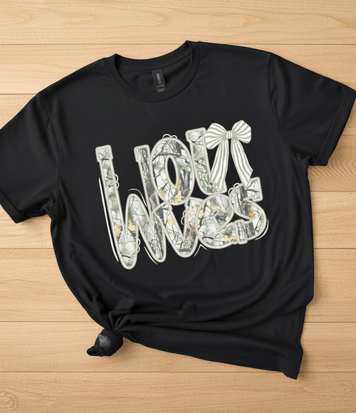 Black graphic T-shirt displayed on a rustic wood background.  Tshirt has camo words for the mascot of a school. 